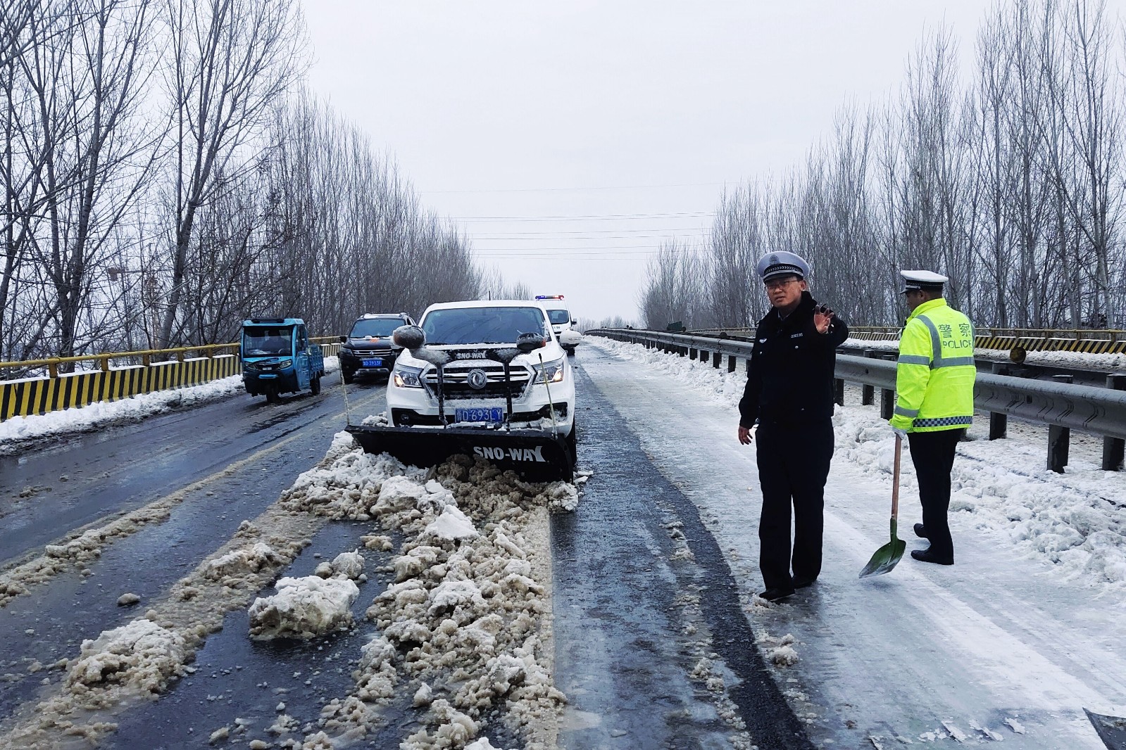 在张汪镇辖区内，民警正在指挥铲雪车辆清理积雪